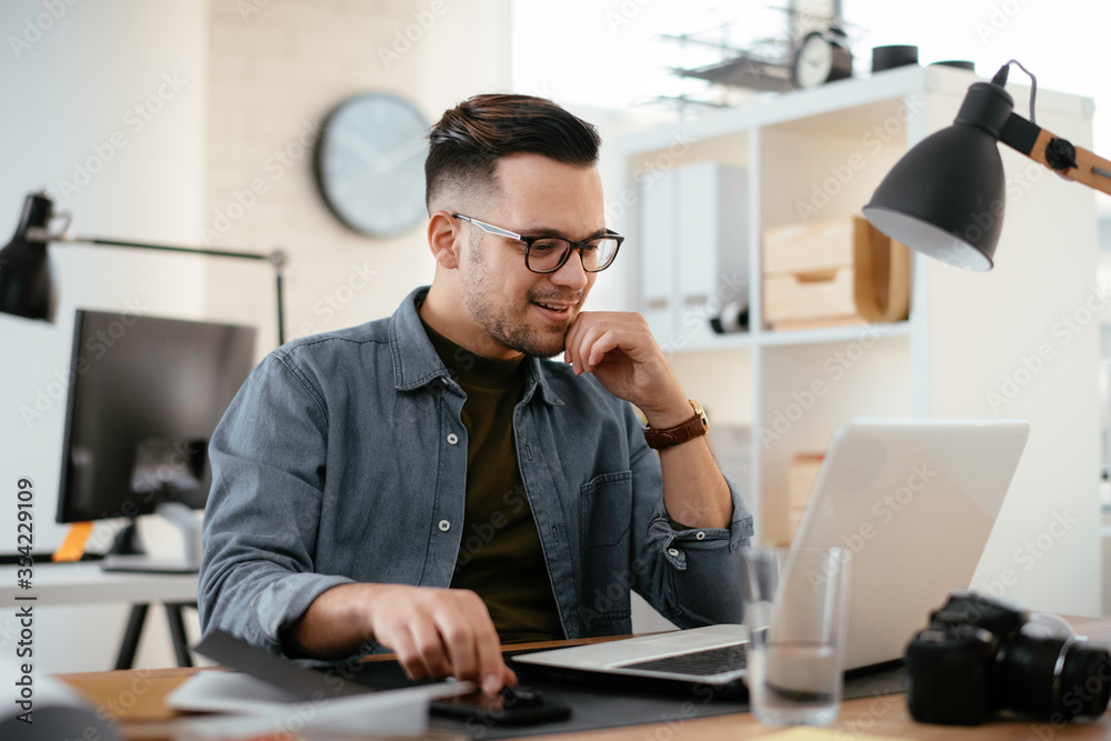 Young businessman using laptop in his office. Handsome man working in office. Young businessman using laptop in his office. Handsome man working in office.