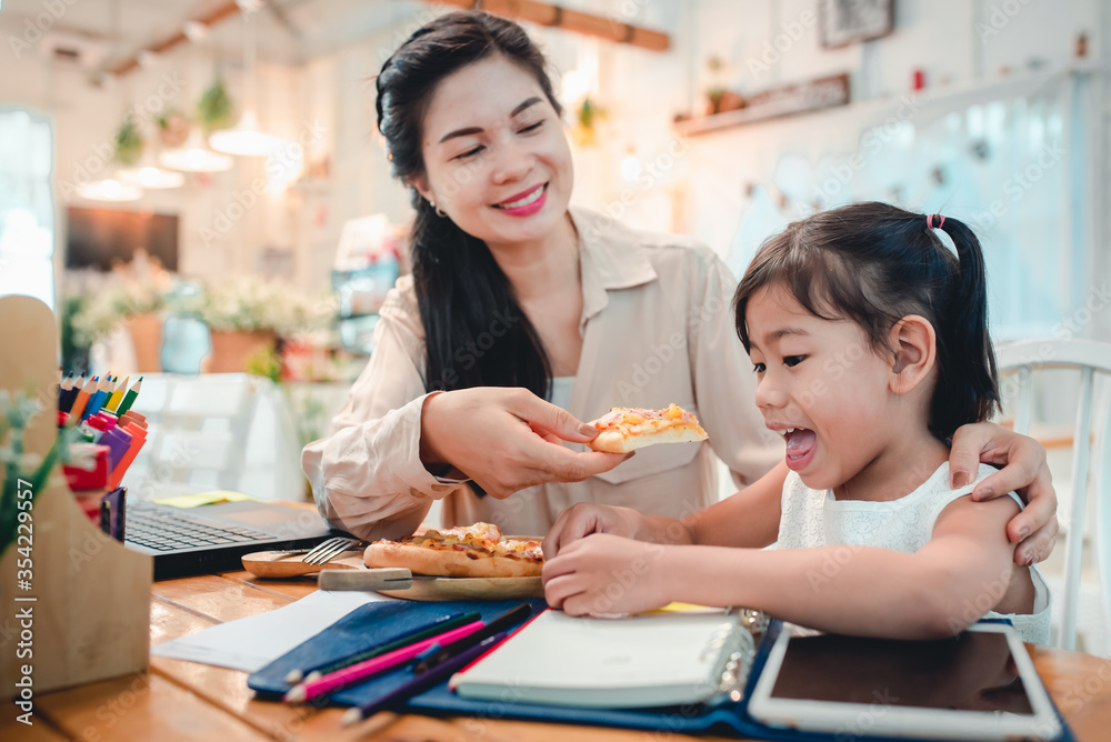 Asian mothers and children do activities at home. Mother is going to feed pizza for her kids who are doing homework and studying online at home. During the virus epidemic, Covid-19 Asian mothers and children do activities at home. Mother is going to feed pizza for her kids who are doing homework and studying online at home. During the virus epidemic, Covid-19
