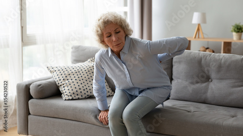 Valokuva Old woman gets up off the sofa feels shooting repeated low back pain caused by s