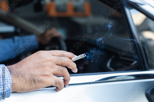 Young man smoking a cigarette in car.