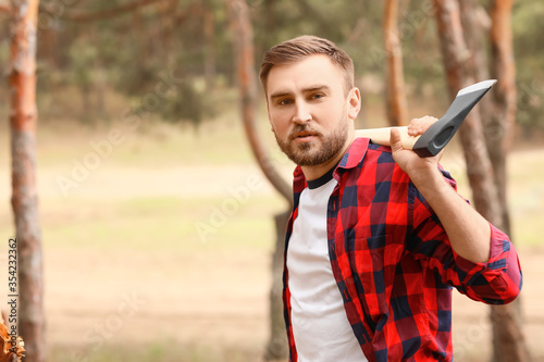 Handsome lumberjack with axe in forest