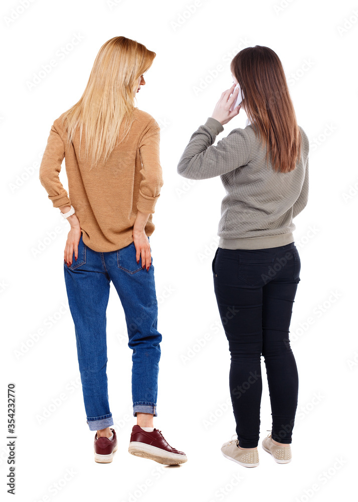 Back view of two young woman photographed on a mobile phone in sweater. Back view of two young woman photographed on a mobile phone in sweater.