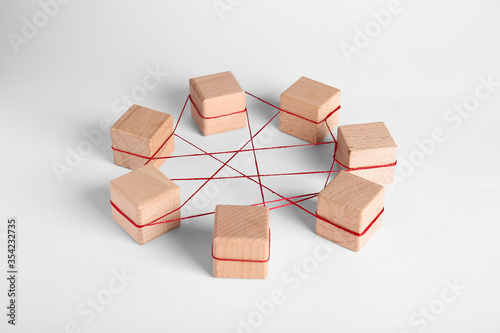 Wooden cubes tied with red thread on light background. Unity concept