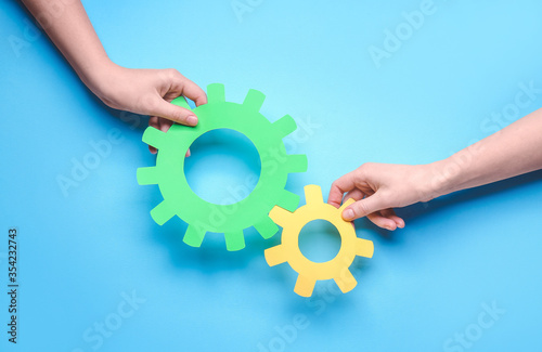 Hands with paper gears on color background. Unity concept