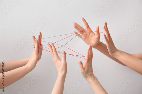 Hands tied with red thread on light background. Unity concept