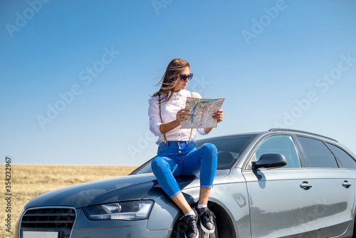 Beautiful woman   view map for travel. Pretty girl standing next to the car. The pleasure of traveling. © RomanR