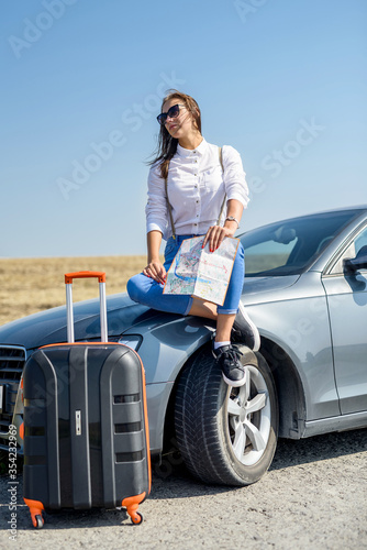 Beautiful woman   view map for travel. Pretty girl standing next to the car. The pleasure of traveling. © RomanR