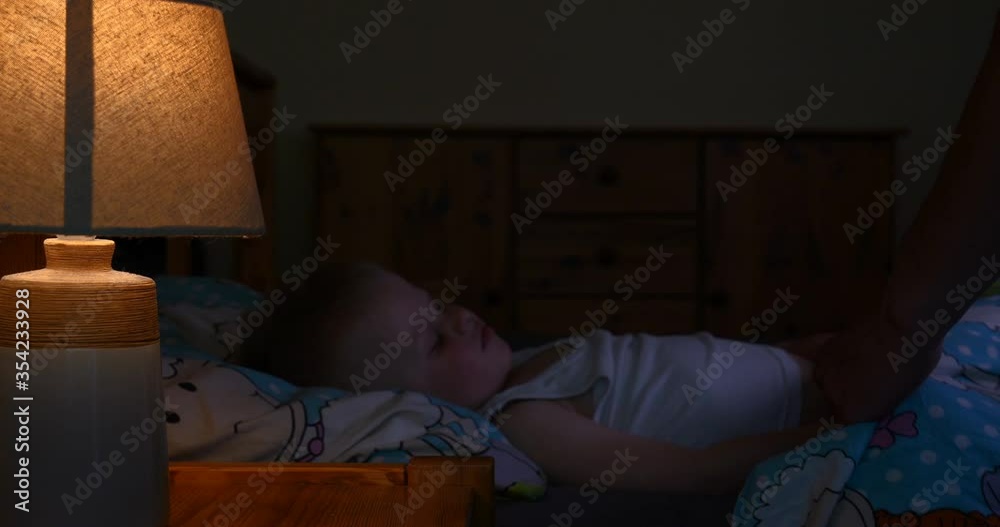 Loving father kissing his baby boy.Father kissing his baby boy forehead while his sleeping and holding hands. Parent love. Loving father kissing his baby boy.Father kissing his baby boy forehead while his sleeping and holding hands. Parent love.