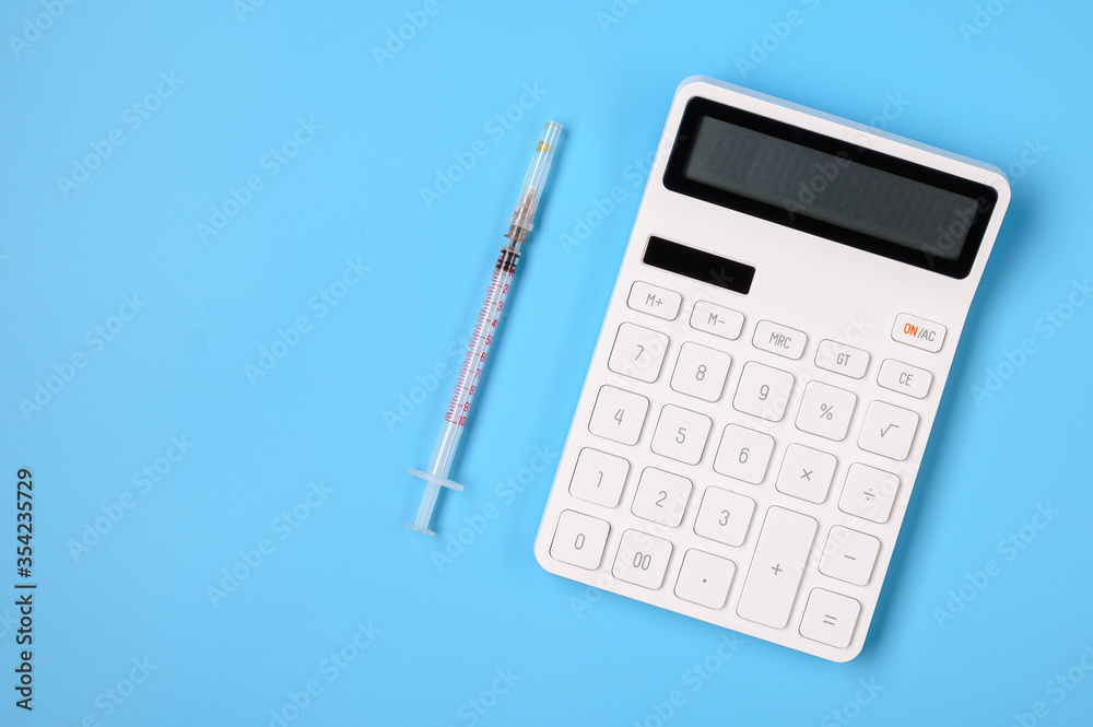 Calculator and syringe on a blue background with place for text. Calculator and syringe on a blue background with place for text.