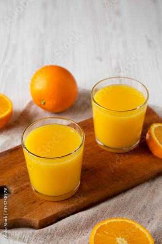 Healthy Orange Juice on a rustic board on a white wooden background, side view. Copy space.