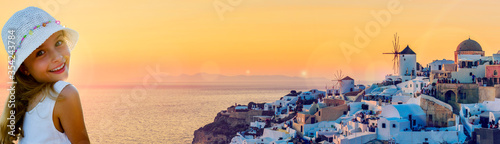 Girl with amazing view with white houses in Oia village on Santorini island in Greece at suset.