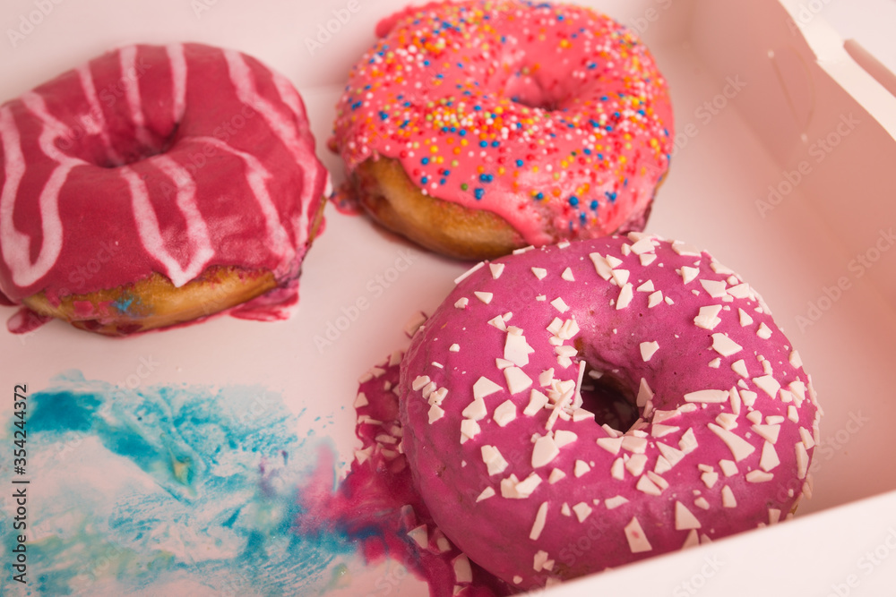 Multi-colored donuts in a white box close-up.