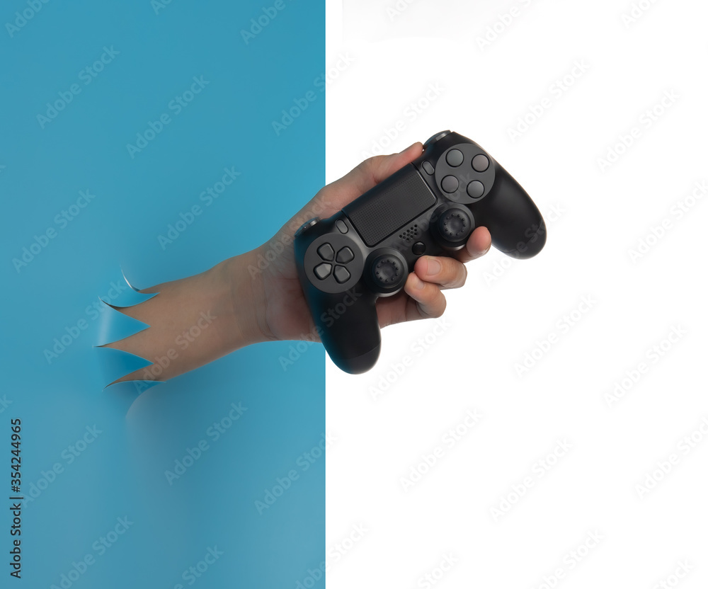 Fototapeta premium Gaming concept,Hand hold new joystick through the torn blue plastic isolated on white background