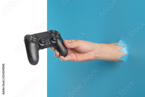 Gaming concept,Hand hold new joystick through the torn blue plastic isolated on white background