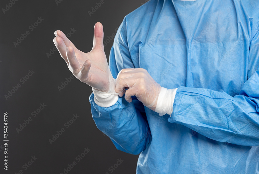 Crop doctor putting on medical gloves in studio Crop doctor putting on medical gloves in studio