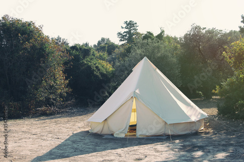 Glamping campsite in the forest. Big camping tent for luxury outdoor vacation. Staycations, hyper-local travel, night camping out concept.