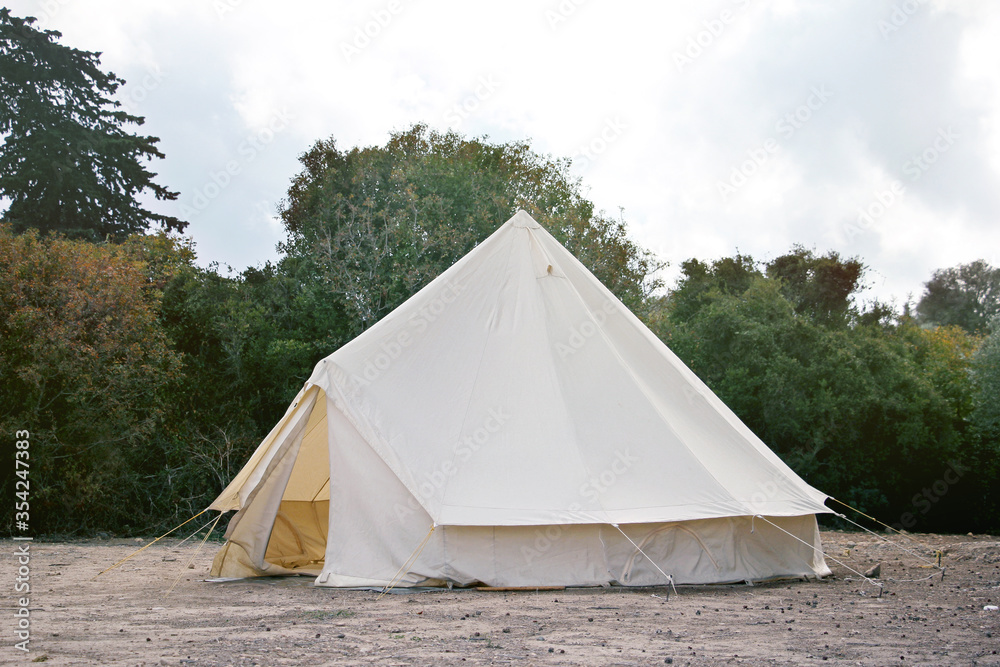 Glamping campsite in the forest. Big camping tent for luxury outdoor vacation. Staycations, hyper-local travel, night camping out concept.