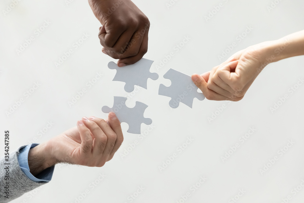 Close up bottom view diverse colleagues holding white pieces of puzzle, finding searching business solution, solving problems together, employees engaged in team building activity, support and help - obrazy, fototapety, plakaty 