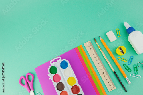School supplies  top view of scissors  paper  watercolour paintings  brush  pen and ruler on the green background