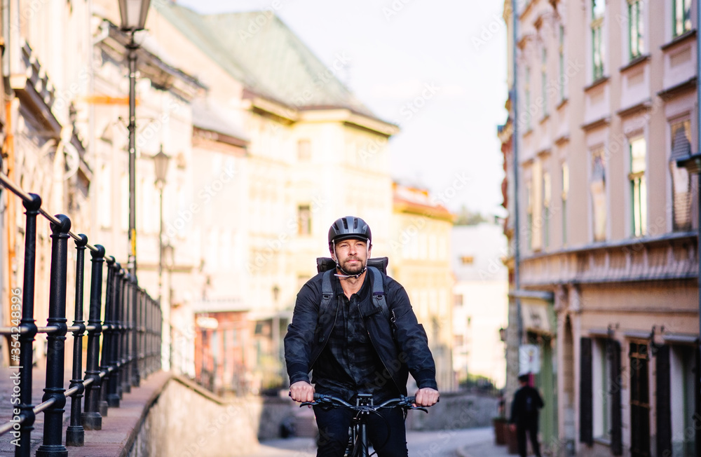 Front view of delivery man courier with bicycle cycling in town.