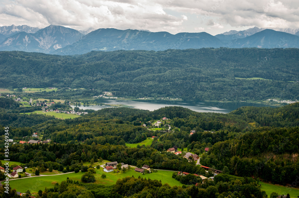 Fototapeta premium Panoramic view of the valley with houses, a river, mountains and clouds