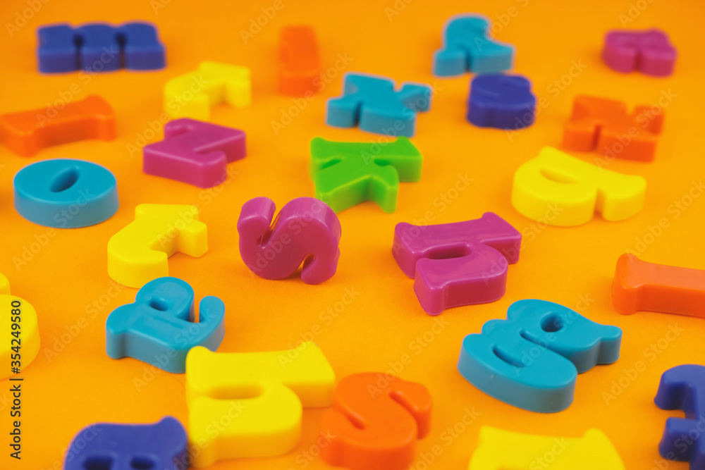 Naklejka premium Plastic colourful alphabet letters on the orange background.