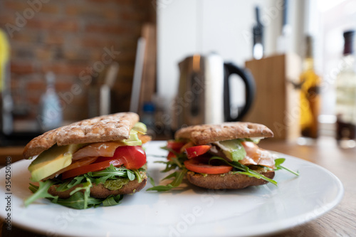 Fresh salmon sandwich with salad close up and avocado and a white plate