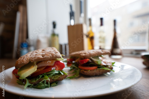 Fresh salmon sandwich with salad close up and avocado and a white plate