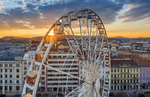 Budapest  Hungary - Aerial view of the famous ferris wheel of Budapest with Buda Castle Royal Palace and an amazing golden sunset and sky. The wheel is totally empty due to the Coronavirus disease