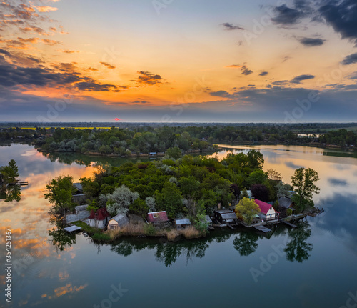 Budapest, Hungary - Aerial view of small fishing island on Lake Kavicsos (Kavicsos to) of Csepel district with a warm sunrise and reflecting clouds. Island is full with fishing huts, piers and cabins