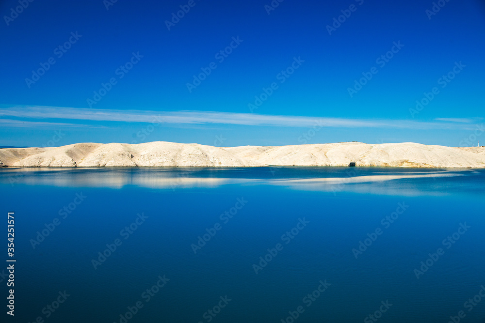 Croatia, Adriatic landscape, rocky desert of Pag island and peaceful seascape in the morning, reflection of stone in water