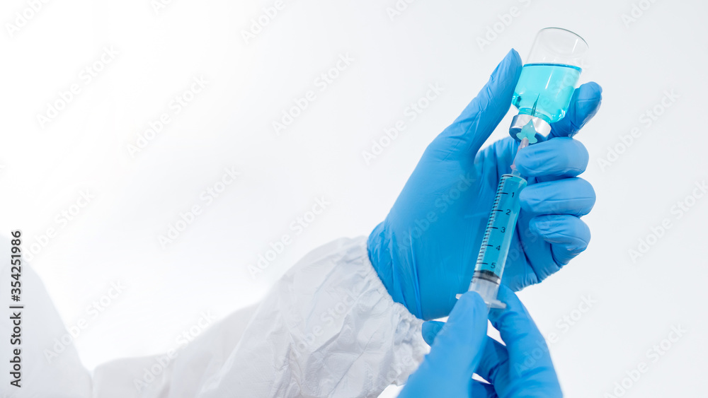 COVID-19 Vaccination concept. Doctor or physician hand in Personal protective equipment suit (PPE) with blue latex gloves holding syringe and medicine vial for Coronavirus vaccine injection. COVID-19 Vaccination concept. Doctor or physician hand in Personal protective equipment suit (PPE) with blue latex gloves holding syringe and medicine vial for Coronavirus vaccine injection.