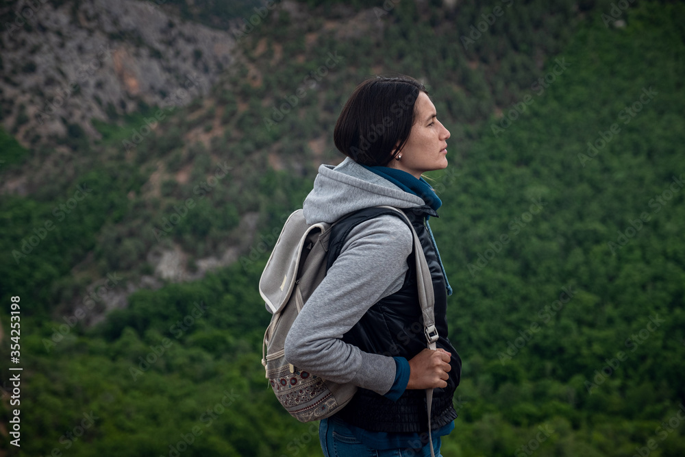 Young traveling woman on the top of the mountain cliff