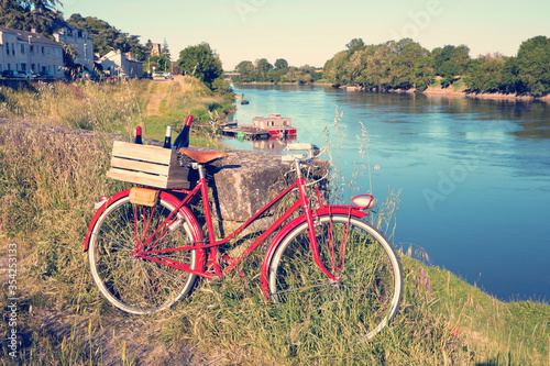 Vieux vélo rouge sur les bord de la Loire en France, caisse de vin rouge sur le porte bagage.