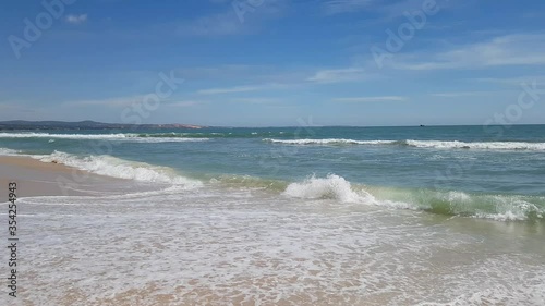 Sea profit on a bright sunny day. Waves wash white sand. Vietnam