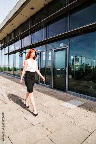 Young girl walks along glass wall of building