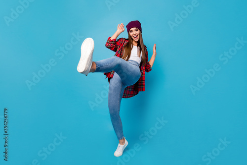 Full length photo of stylish good mood pretty lady glad warm spring weather rejoicing students party raise leg dance wear casual hat plaid shirt jeans shoes isolated blue color background