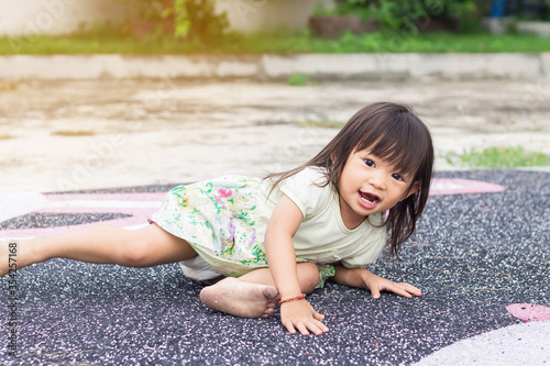 Asian baby child girl falling and laying on the floor grass field ground. Development of baby aged of one year old. Kid Exercise for health.