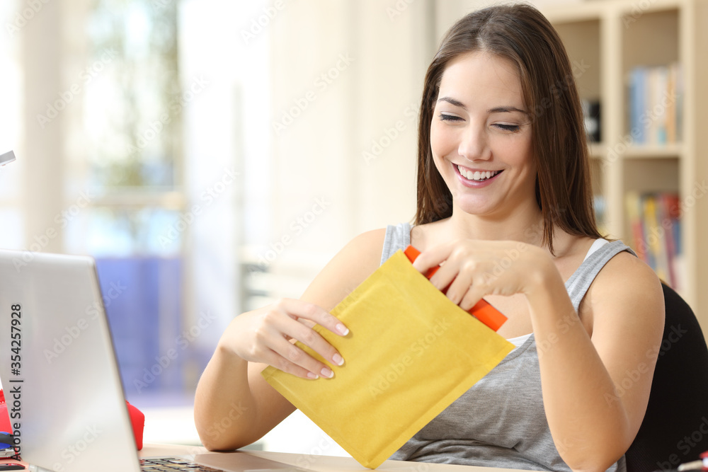 Happy student opening padded envelope at home Happy student opening padded envelope at home