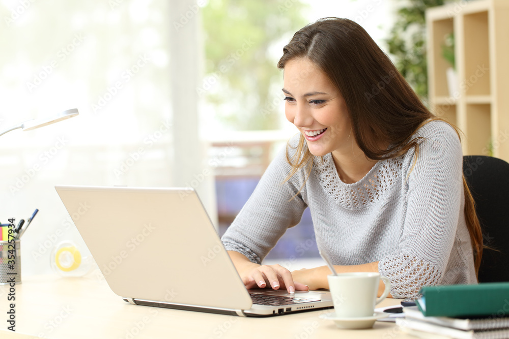 Happy student reading content on a laptop at home Happy student reading content on a laptop at home