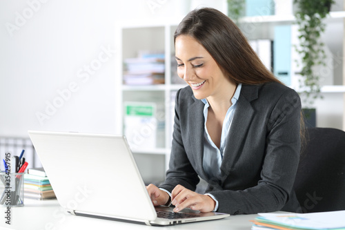 Happy executive woman typing on laptop at the office