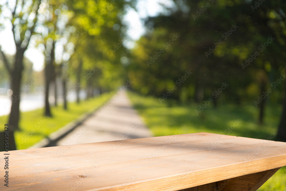 Fototapeta premium Empty wooden deck table with park bokeh background.