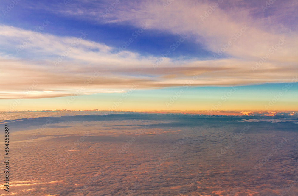 Panorama view of fluffy clouds on sunset sky view from flying airplane