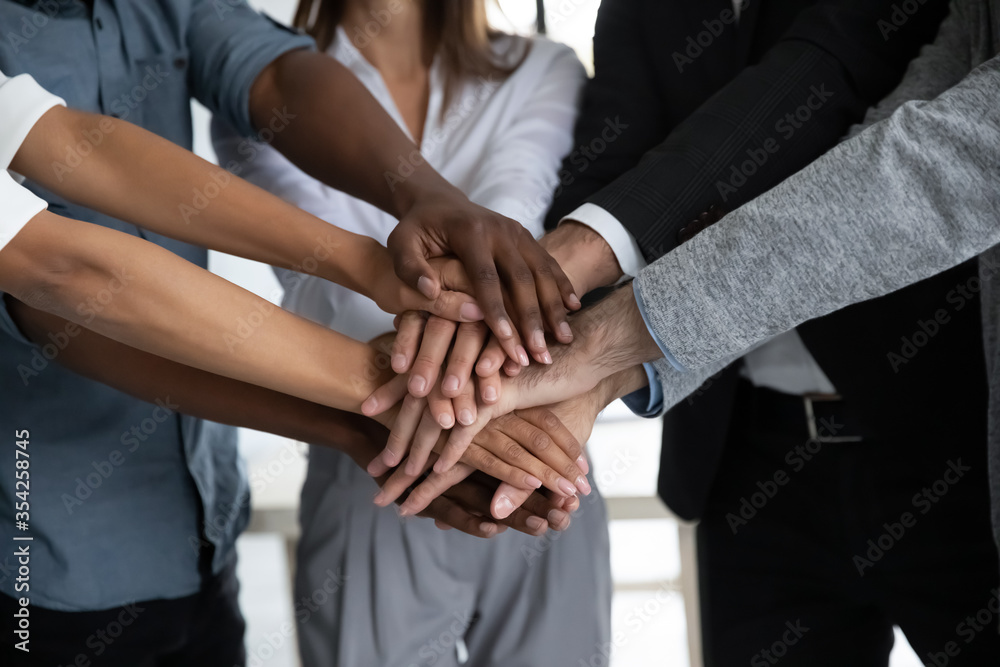 Close up diverse colleagues stacking hands, showing unity and support, successful employees team celebrating achievement, sharing success, engaged in team building activity at briefing Close up diverse colleagues stacking hands, showing unity and support, successful employees team celebrating achievement, sharing success, engaged in team building activity at briefing