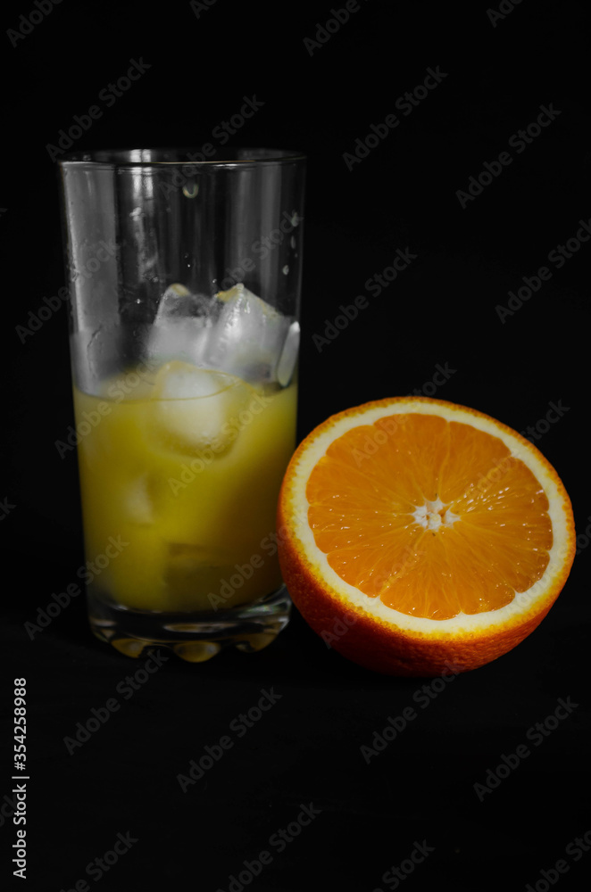 glass of freshly squeezed orange juice with ice on black background glass of freshly squeezed orange juice with ice on black background