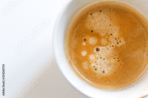 Brown coffee italian espresso cup with foam on top on white background