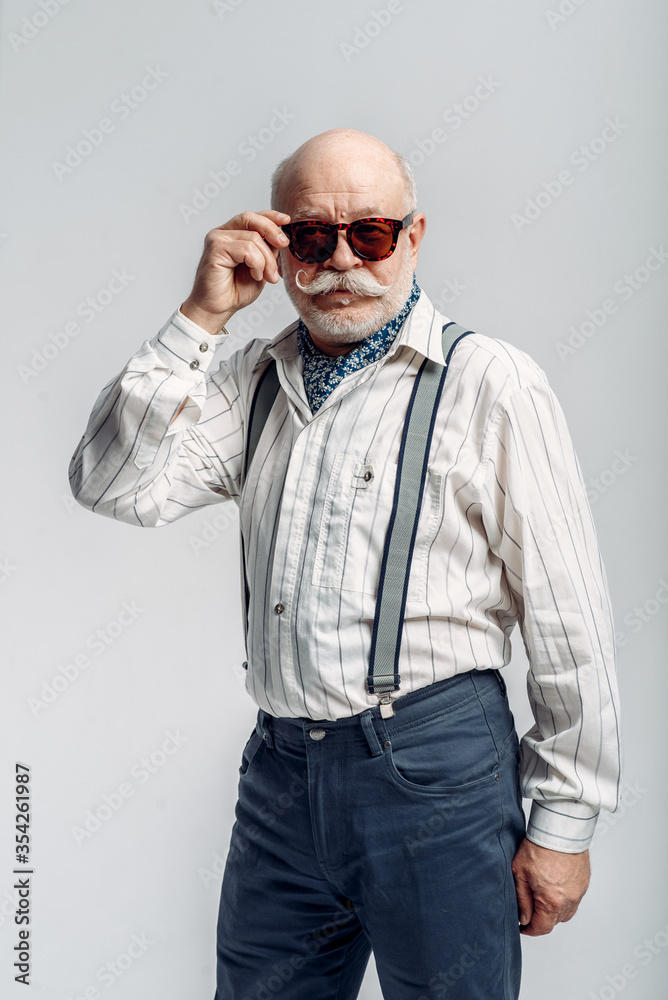 Elderly man with mustache poses in sunglasses