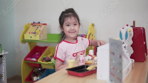 Little asian girl playing wooden blocks in living room at home