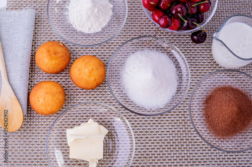 Ingredients for making homemade cupcakes with chocolate and cherries.