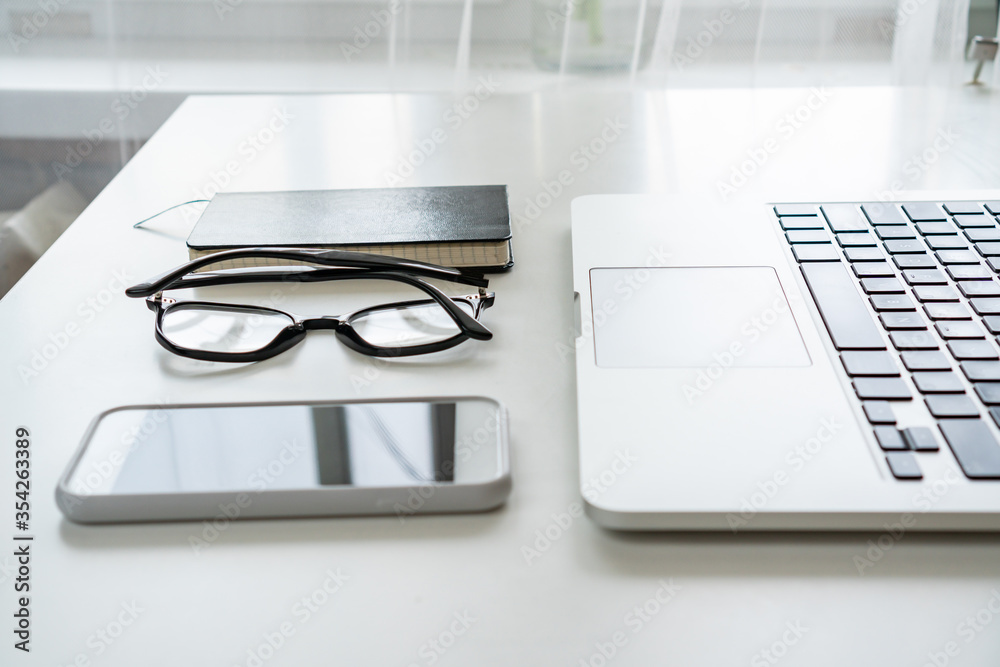 on the desktop is a mobile phone, glasses, a notebook and a computer on the desktop is a mobile phone, glasses, a notebook and a computer
